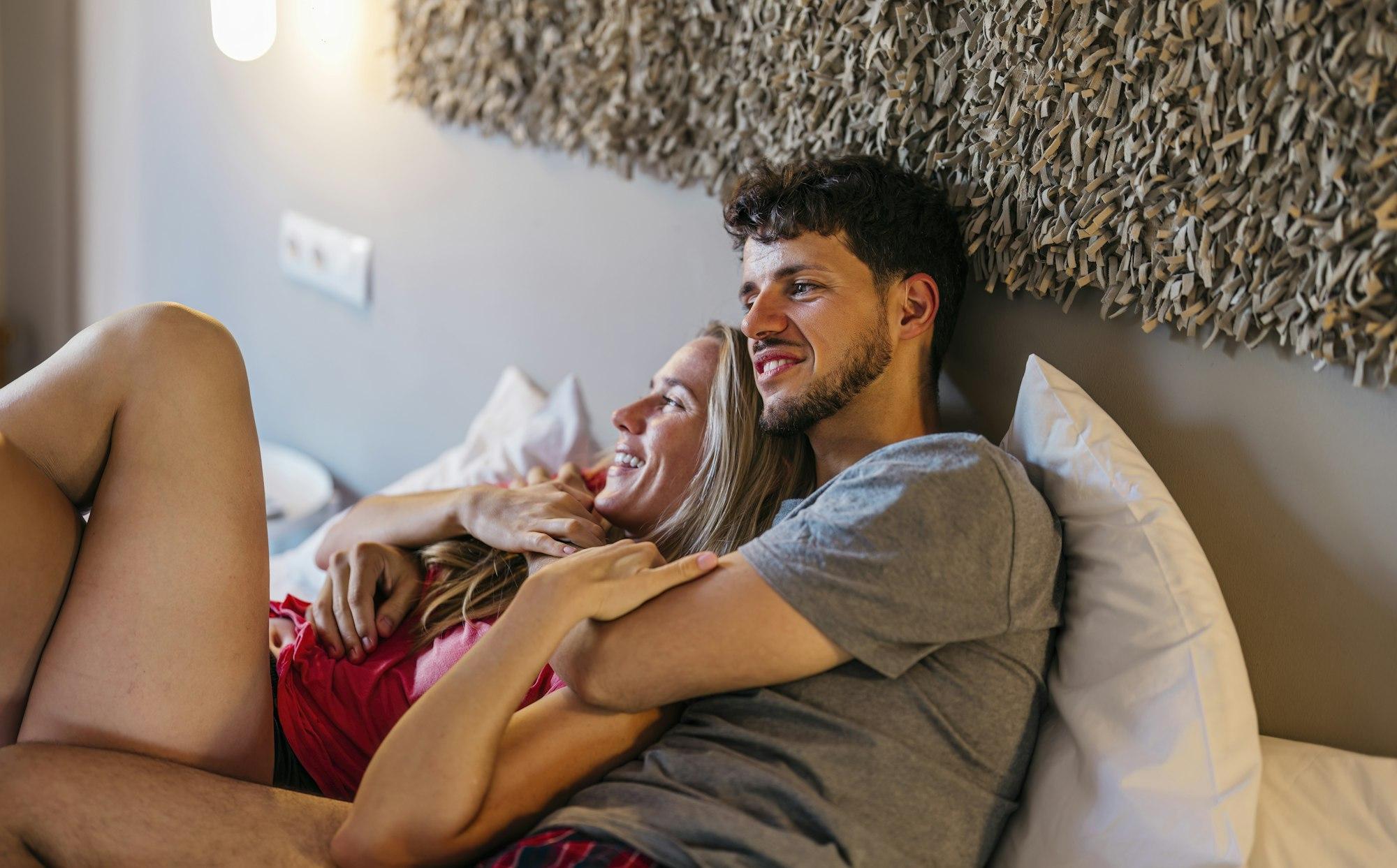 multiracial couple cuddling in bed on vacation